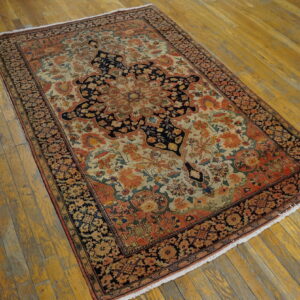 Ornate low-pile rug featuring a navy, rust, and cream medallion pattern on worn wooden plank flooring.