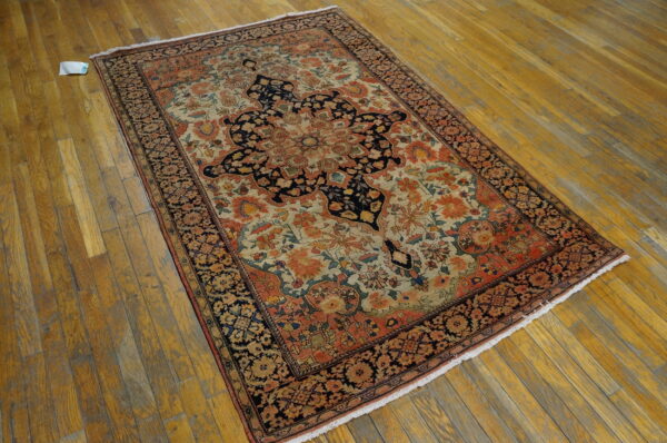 Ornate low-pile rug featuring a navy, rust, and cream medallion pattern on worn wooden plank flooring.