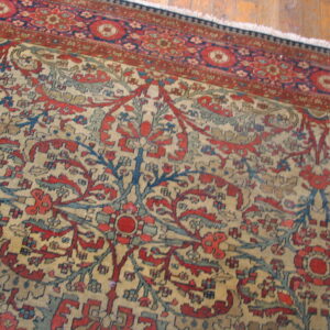 Red, blue, and beige ornate traditional rug with a detailed floral pattern resting on hardwood flooring.