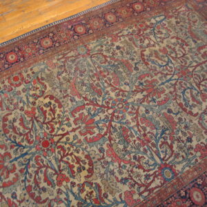 Ornate red and blue floral patterned rug with a cream field on a light honey-colored wood floor.