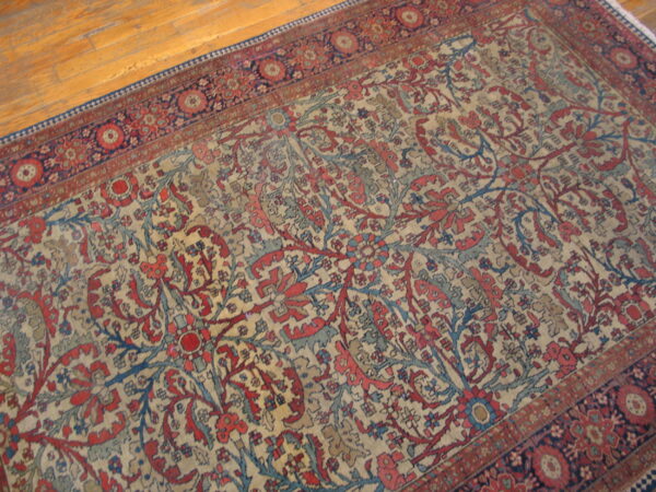 Ornate red and blue floral patterned rug with a cream field on a light honey-colored wood floor.
