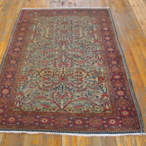 Traditional rug with dense red, blue, and tan floral patterns centered on worn wood floorboards.