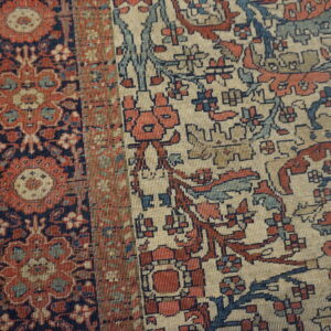 Ornate patterned rug detail showing colors of cream, terracotta, navy, and soft blue.
