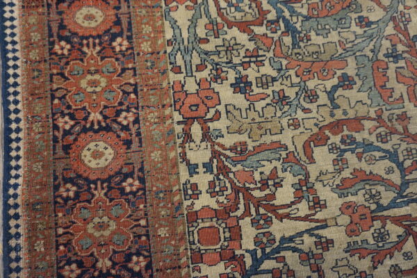 Ornate patterned rug detail showing colors of cream, terracotta, navy, and soft blue.
