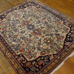 Traditional cream rug with rust, light blue, and navy floral designs on distressed hardwood floors.