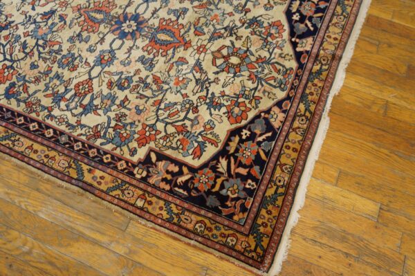 Traditional ivory rug with navy, rust, and gold floral patterns rests on distressed wood floorboards.