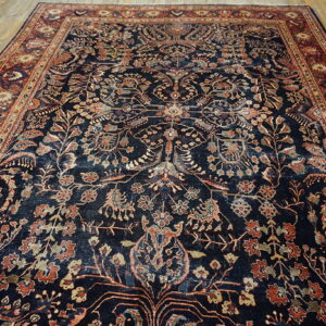 A large, intricately patterned navy rug with rust-red borders lies on light wooden plank floors.
