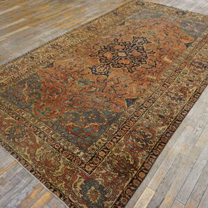 Ornate area rug in rust, navy, and gold with a central medallion on distressed plank flooring.