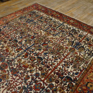 Traditional rug with dense red, blue, and gold floral pattern on an ivory ground, displayed on wood planks.