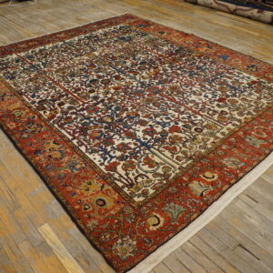 Low-pile rug with an ivory field, botanical patterns, and wide reddish-orange borders on wood planks.