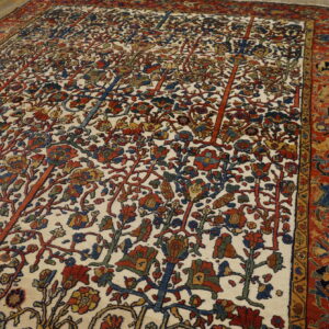 Detailed rug with a cream field, multicolored botanical patterns, and a wide red border, lying on wood floors.