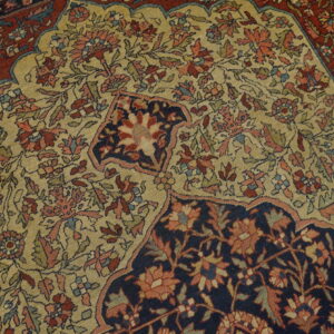 Intricate floral rug pattern with a light gold center, dark navy detail, and deep red border.
