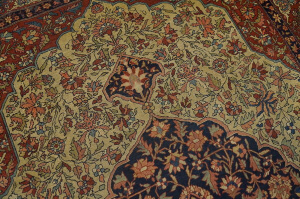 Intricate floral rug pattern with a light gold center, dark navy detail, and deep red border.