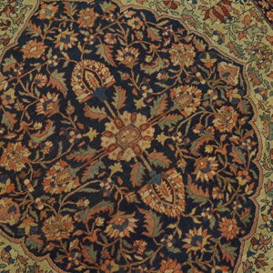 Intricate floral rug detail showing a dark blue medallion surrounded by rust and sage green patterns.