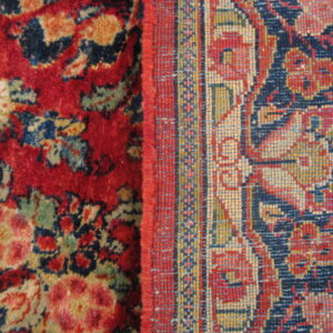 Detailed view showing two contrasting rug patterns, a high-pile red floral and a low-pile navy geometric border.