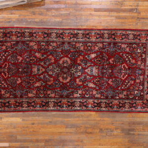 Traditional red runner rug with dense multicolored floral patterns rests on light hardwood floors.