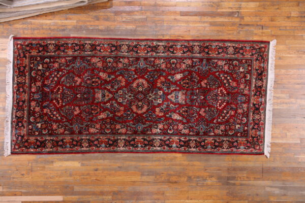 Traditional red runner rug with dense multicolored floral patterns rests on light hardwood floors.
