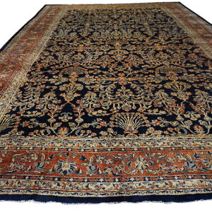 Navy blue rug with all-over tan, rust, and teal floral motifs and thick ornamental borders.