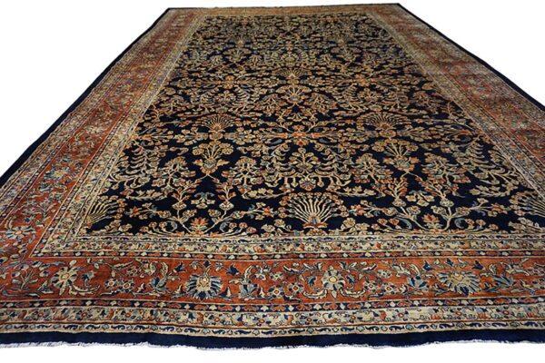 Navy blue rug with all-over tan, rust, and teal floral motifs and thick ornamental borders.