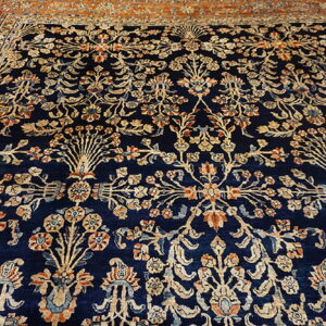 Dark blue traditional rug with a detailed repeating floral pattern in cream, rust, and orange.