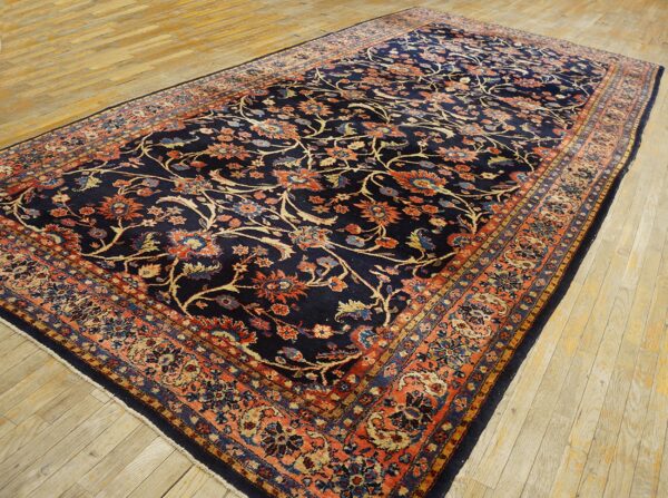 Ornate navy blue rug featuring rust-colored floral motifs and a detailed border on light wood flooring.