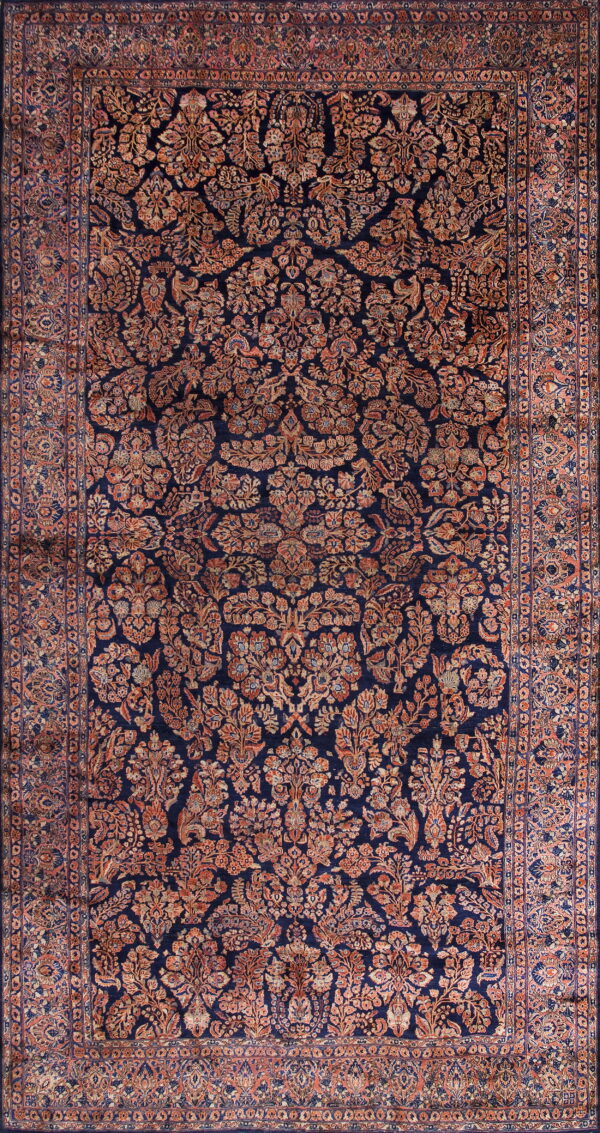 Navy blue area rug featuring a dense, traditional floral pattern in muted rust and terracotta tones.