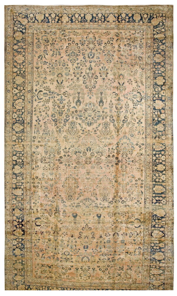 Pale pink and beige rug with dense blue floral designs and a wide, contrasting navy blue border.