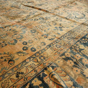 Distressed traditional rug featuring golden tan, indigo blue, and rust floral patterns and multiple borders.