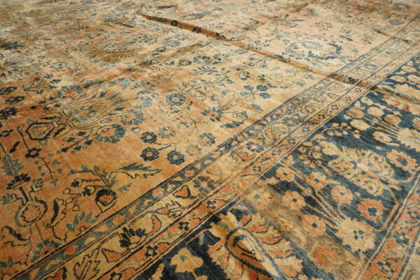 Distressed traditional rug featuring golden tan, indigo blue, and rust floral patterns and multiple borders.