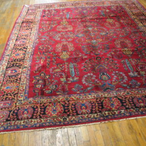 A large, deep red rug with dense floral and bird motifs covers a glossy plank wood floor.