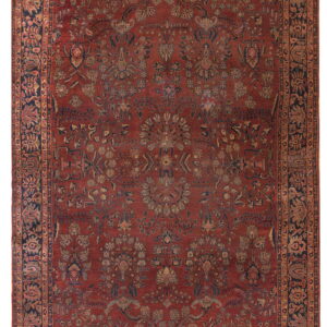 Ornate, low-pile rug featuring a dense floral pattern in a distressed red, navy, and gold color palette.
