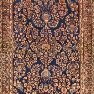 Full view of a low-pile rug with a navy center field and terracotta border framing symmetrical botanical designs.