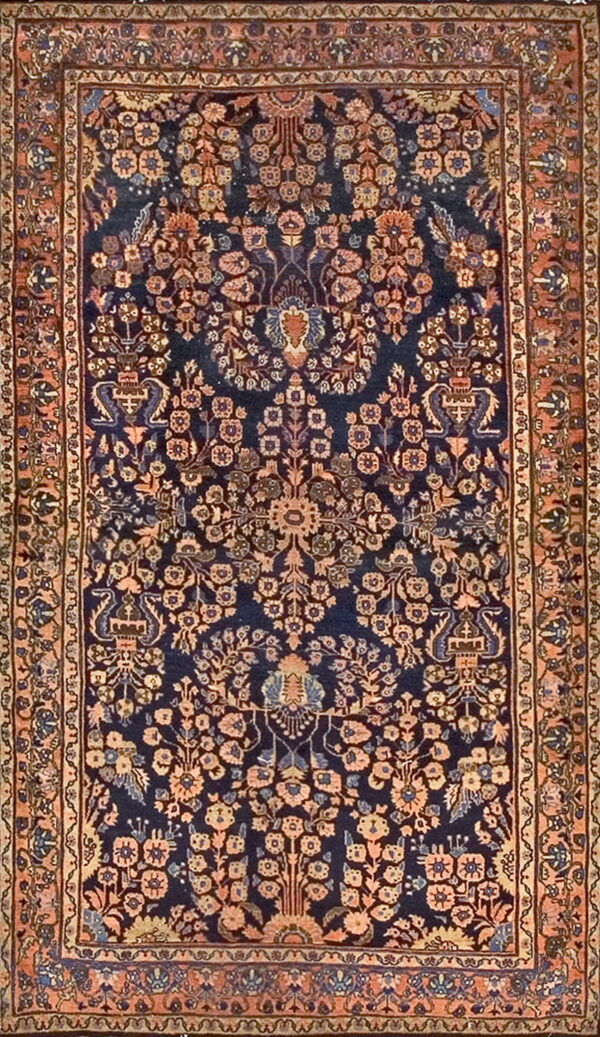 Full view of a low-pile rug with a navy center field and terracotta border framing symmetrical botanical designs.