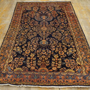Ornate, dark blue area rug with orange floral patterns rests on a light golden hardwood floor.