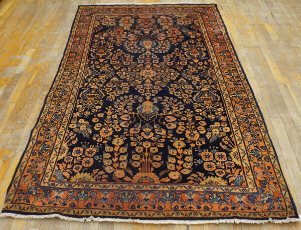 Ornate, dark blue area rug with orange floral patterns rests on a light golden hardwood floor.
