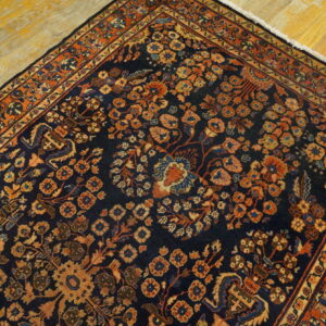 Dark blue rug with a detailed rust and orange botanical design, partially visible on distressed wooden planks.