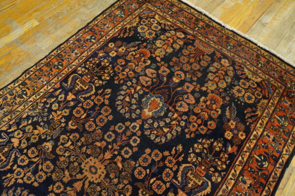 Dark blue rug with a detailed rust and orange botanical design, partially visible on distressed wooden planks.