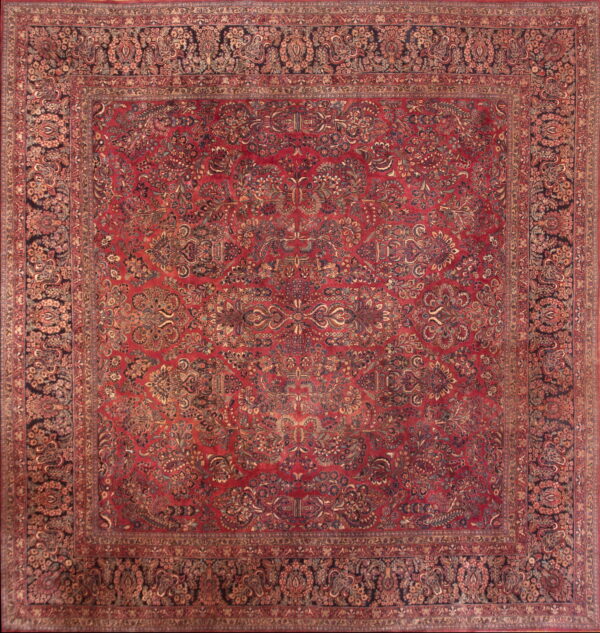 Detailed view of a square rug with a dense red and black traditional floral pattern and ornate borders.