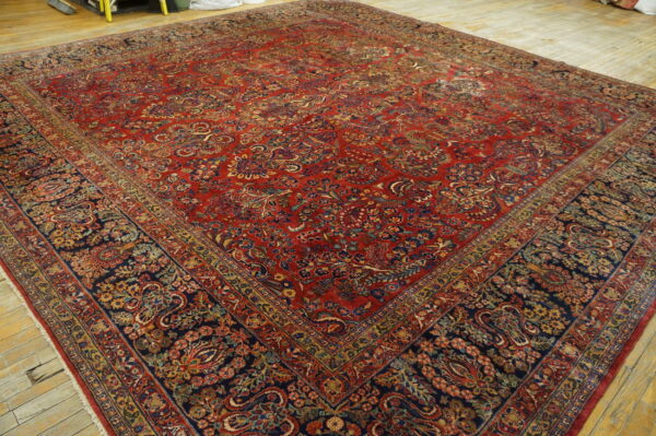 Ornate red and navy traditional rug with gold and blue accents covers light distressed wooden plank flooring.