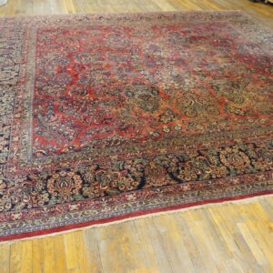 Ornate traditional red and blue rug with a complex floral design displayed flat on bright hardwood flooring.