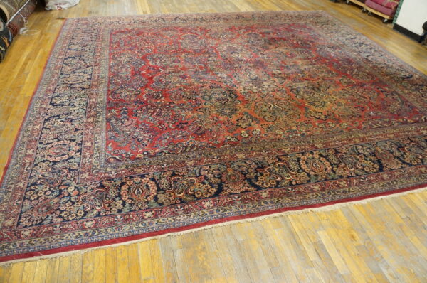 Ornate traditional red and blue rug with a complex floral design displayed flat on bright hardwood flooring.