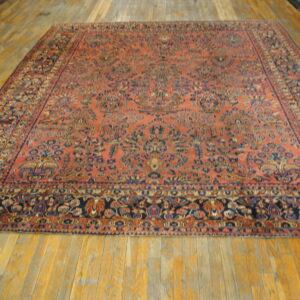 A large, rectangular coral and navy patterned rug lies flat on wide wooden floorboards.