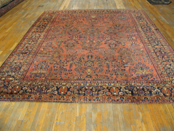 A large, rectangular coral and navy patterned rug lies flat on wide wooden floorboards.