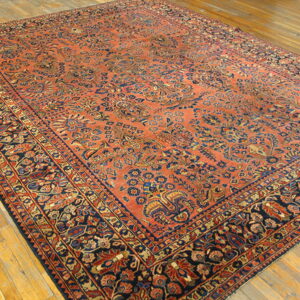 Traditional rug with a dense all-over pattern in coral, navy, and gold on light hardwood floors.