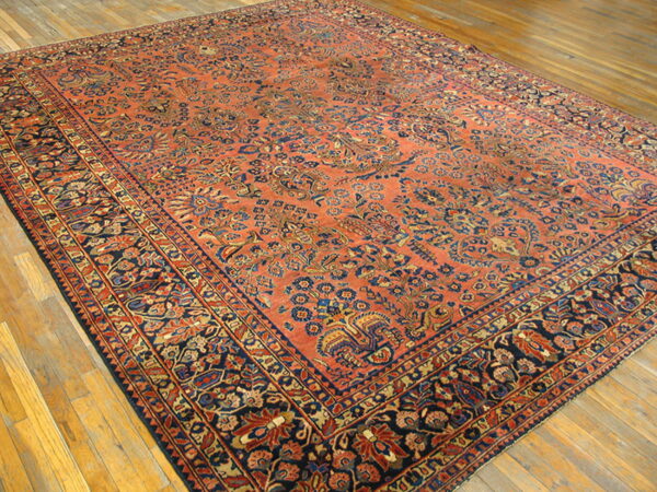 Traditional rug with a dense all-over pattern in coral, navy, and gold on light hardwood floors.