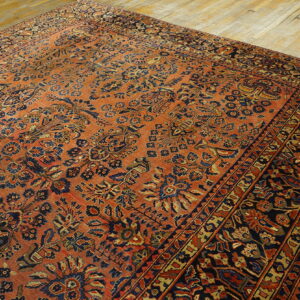 Traditional patterned rug featuring rust and navy botanical motifs on distressed wood floors.