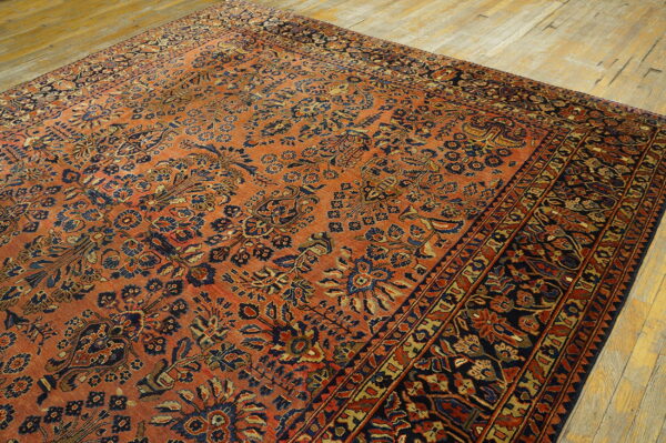 Traditional patterned rug featuring rust and navy botanical motifs on distressed wood floors.