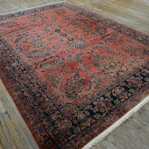 Large red and navy rug with intricate traditional patterns lies on rustic gray wood planks.