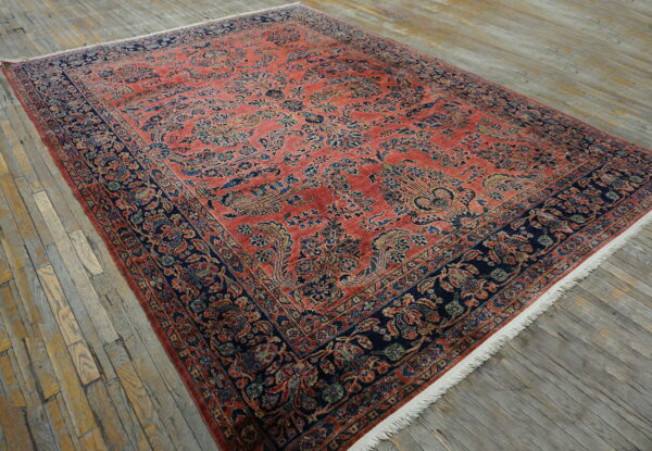 Large red and navy rug with intricate traditional patterns lies on rustic gray wood planks.