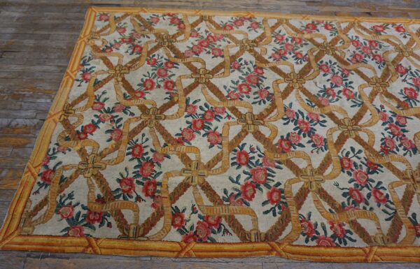 Low-pile rug with interlocking yellow ribbons, red roses, and a gold border on rustic wood flooring.